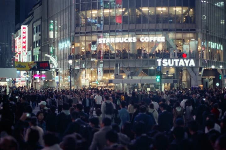 明るい建物前の夜の人波