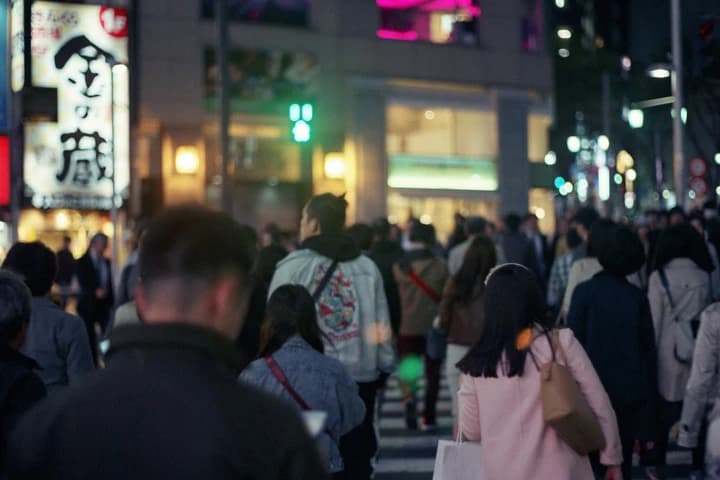 看板の灯りの下を歩く人たち